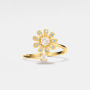 Gold flower-shaped ring with gemstones on a light gray background