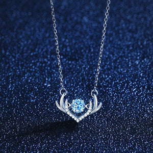 Silver necklace with a heart-shaped pendant featuring a blue gemstone on a dark blue glittery background.