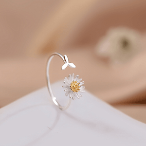 Silver ring with a daisy flower design on a white surface