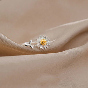 Silver daisy-shaped earring on a beige fabric background