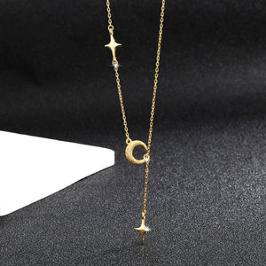 Gold necklace with star and moon pendants on a black background