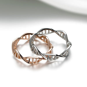 Two interlocking rings, one rose gold and one silver, on a light gray background.