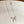 Silver bow-shaped necklace on a white surface