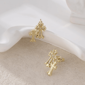 Gold cross earrings on a white surface
