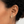 Gold cross earring worn by a person with dark hair.