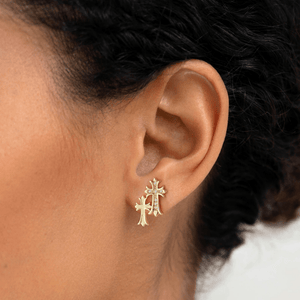 Gold cross earring worn by a person with dark hair.