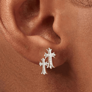 Silver cross earring worn on an ear