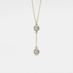 Gold necklace with two circular pendants on a light gray background