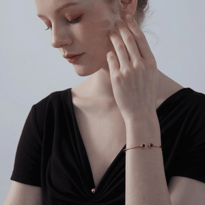 A model wearing a gold-plated sterling silver bangle bracelet with two circular photo projection charms.