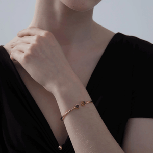 A model wearing a gold-plated sterling silver bangle bracelet with two circular photo projection charms.