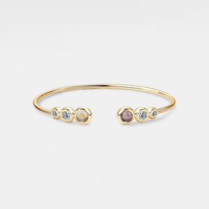 Gold bracelet with embedded stones on a light gray background