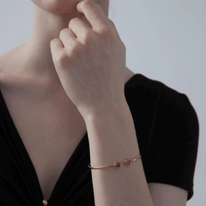 A model wearing a gold-plated sterling silver bangle bracelet with two circular photo projection charms.
