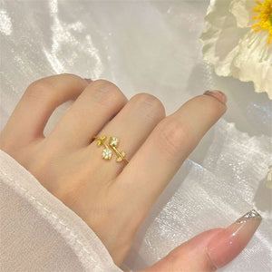 Two tulip flower stacking bypass rings, one plated in gold and the other in silver, with cubic zirconia stones, displayed against a neutral background.