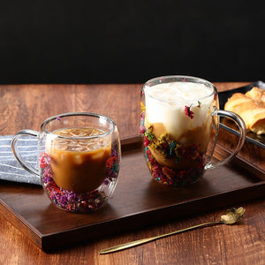 Two glass mugs with floral decorations on a wooden tray with a dark background