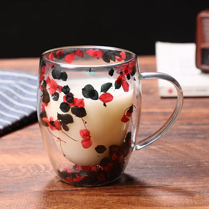 A glass coffee cup with a floral pattern, specifically red and pink flowers, with a creamer or milk substitute visible inside the cup.