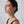 Woman wearing a gold earring on a plain background