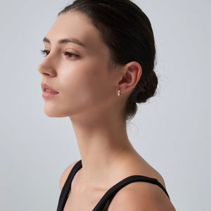 Woman wearing a gold earring on a plain background