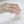 Close-up of a hand wearing a delicate ring on a soft white background
