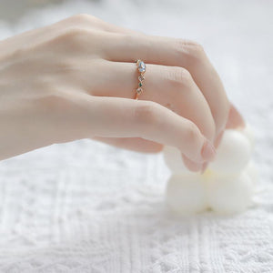Close-up of a hand wearing a delicate ring on a soft white background