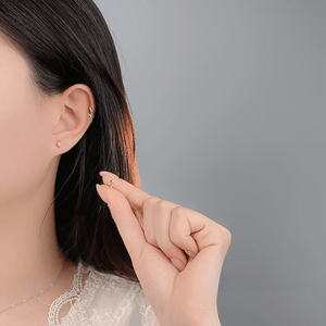 Person wearing gold earrings with a plain background