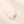 Rose gold necklace with a delicate pendant on a beige background