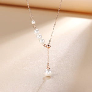 Pearl necklace with rose gold accents on a beige background