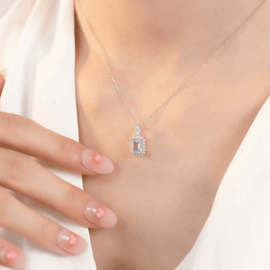 Silver necklace with a pendant worn by a person, against a neutral background