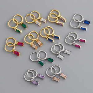 Set of small hoop earrings with colorful gemstones on a gray background