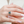 Close-up of a hand wearing a ring with a green gemstone on a blurred background