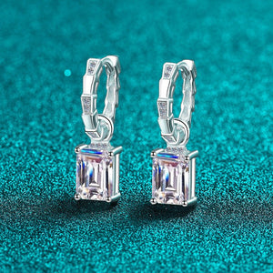 Silver hoop earrings with rectangular gemstones on a teal background
