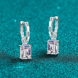 Silver hoop earrings with rectangular gemstones on a teal glitter background