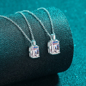 Two diamond pendants on silver chains against a teal background