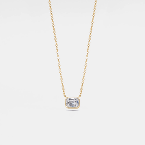 An emerald cut moissanite stone set in a silver and gold necklace with a chain.