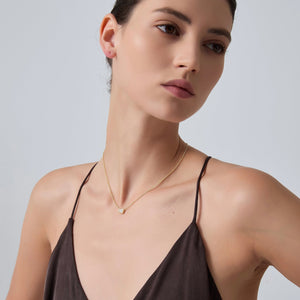 Woman wearing a gold necklace against a plain background