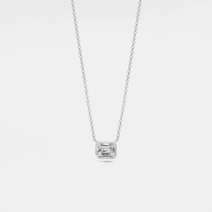An emerald cut moissanite stone set in a silver and gold necklace with a chain.