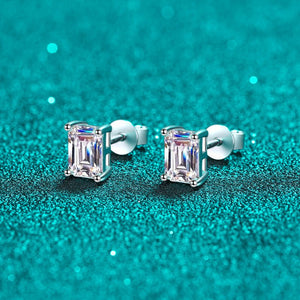 Pair of silver stud earrings with clear gemstones on a teal glittery background