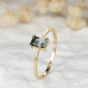 Gold ring with a green gemstone on a textured white background