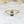 Gold ring with a green gemstone on a white marble background