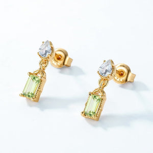 Gold earrings with green gemstones on a white background