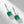 Pair of emerald green earrings with silver and diamond accents on a light gray background