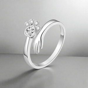 Silver ring with paw print design on a gray background