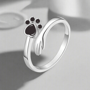 Silver ring with a paw print design on a light gray background