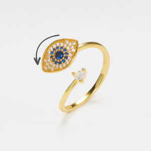A gold-plated sterling silver fidget spinner ring with a blue and clear cubic zirconia evil eye design