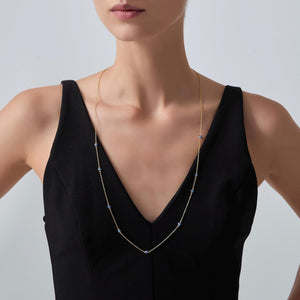 Woman wearing a delicate necklace against a plain background