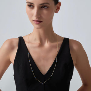 Woman wearing a delicate necklace against a plain background