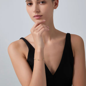 Woman wearing a gold bracelet on a plain background