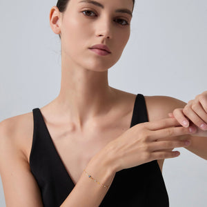Woman wearing a gold bracelet on a plain background