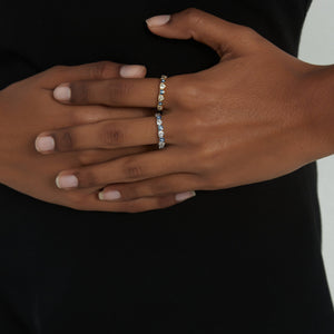 Woman wearing gold and silver stacking rings with blue enamel evil eyes and heart-shaped cubic zirconia accents