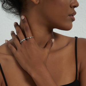 Woman wearing gold and silver stacking rings with blue enamel evil eyes and heart-shaped cubic zirconia accents