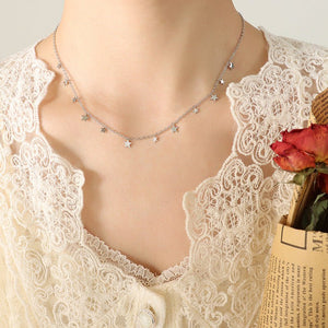 Star-shaped necklace on a mannequin with a lace garment and red flowers.